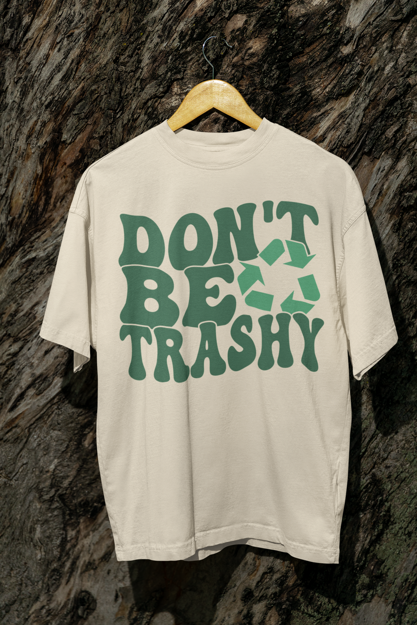a beige t-shirt on a hanger that says "Don't be Trashy" on it with a recycle sign