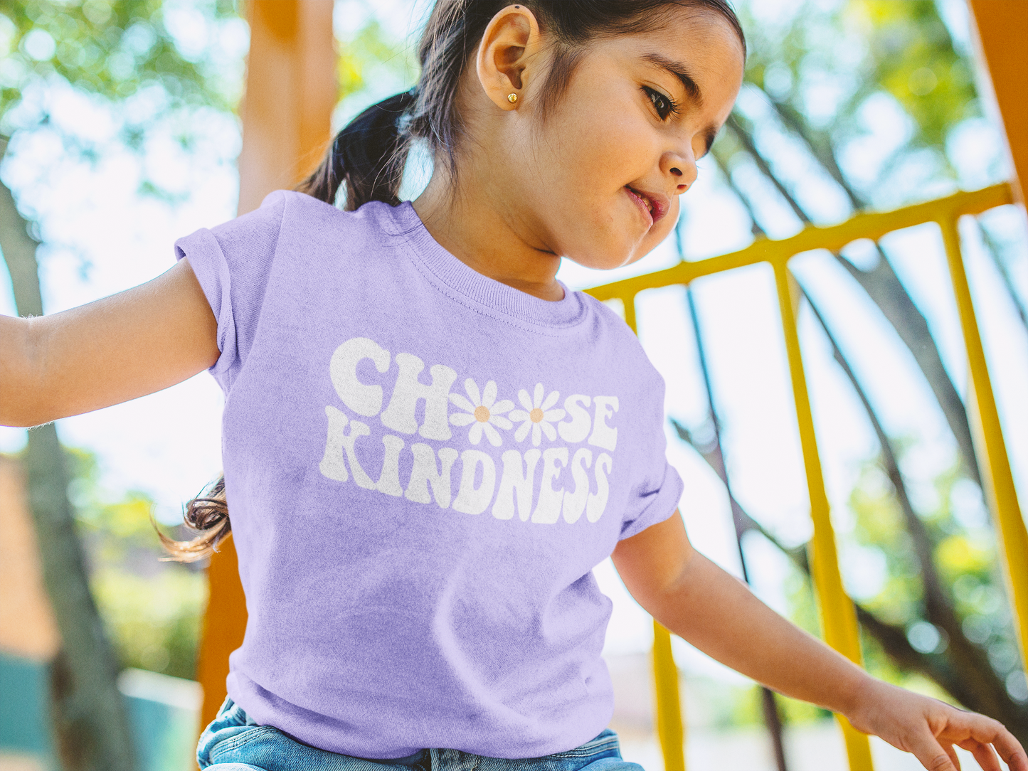 A child outside wearing a "Choose Kindness: purple t-shirt where the letter O is replaced with flowers