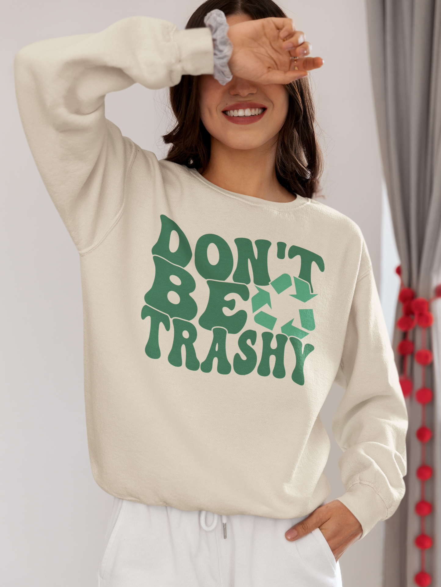 A girl covering her eyes wearing a beige "Don't Be Trashy" Sweatshirt