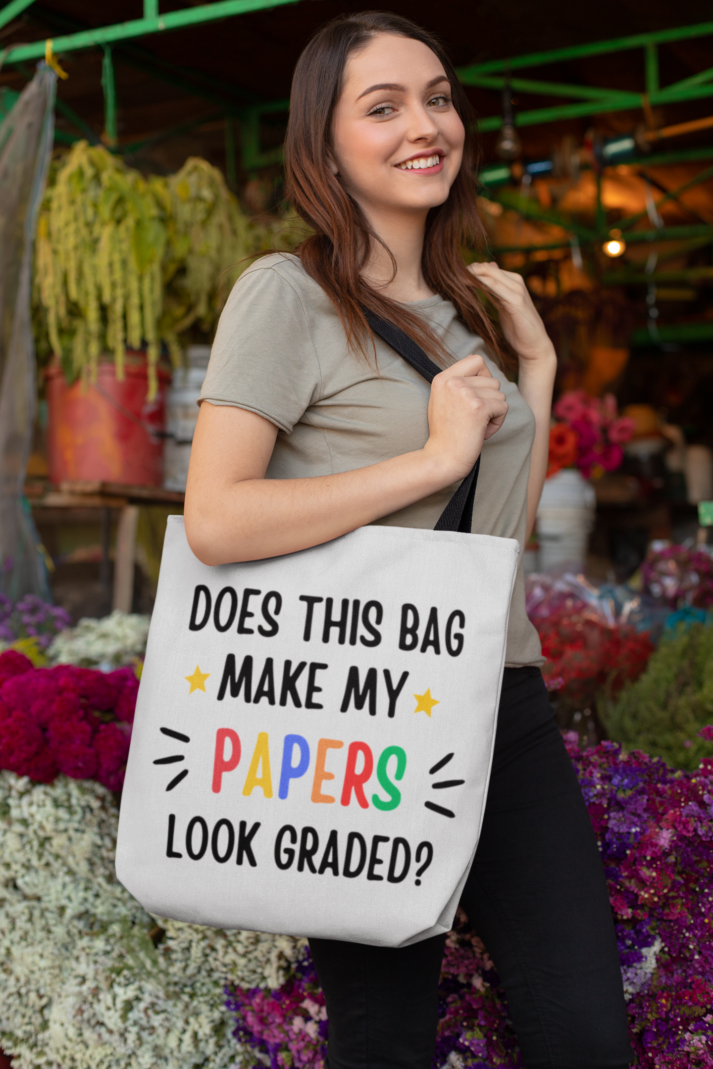 A woman smiling wearing a "Does this make my papers look graded?" tote bag