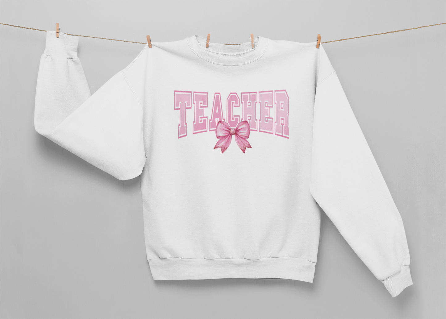 a white sweatshirt that says Teacher with a bow