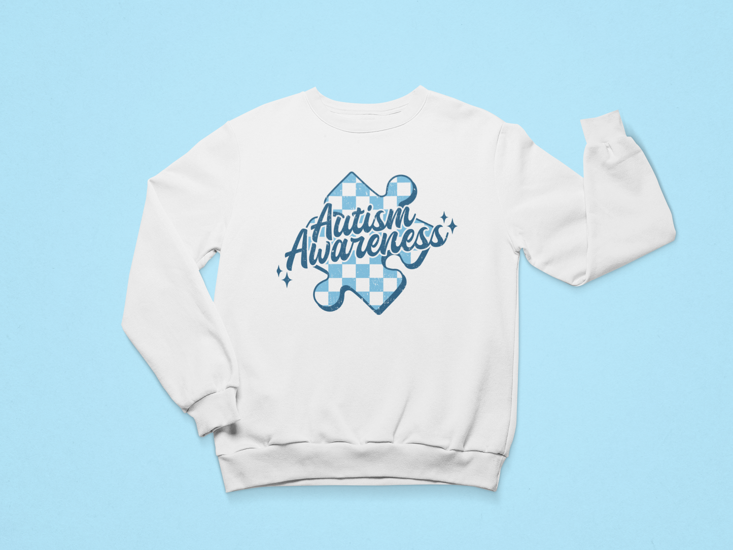 A white sweatshirt that says "autism Awareness" on it with a blue checkered puzzle piece behind the quote. 