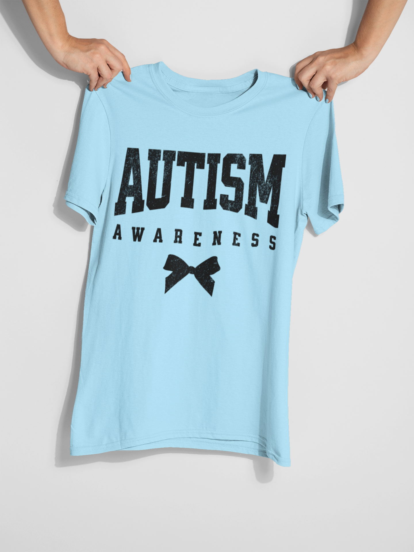 A person holding a blue T-shirt  that says "Autism Awareness" 