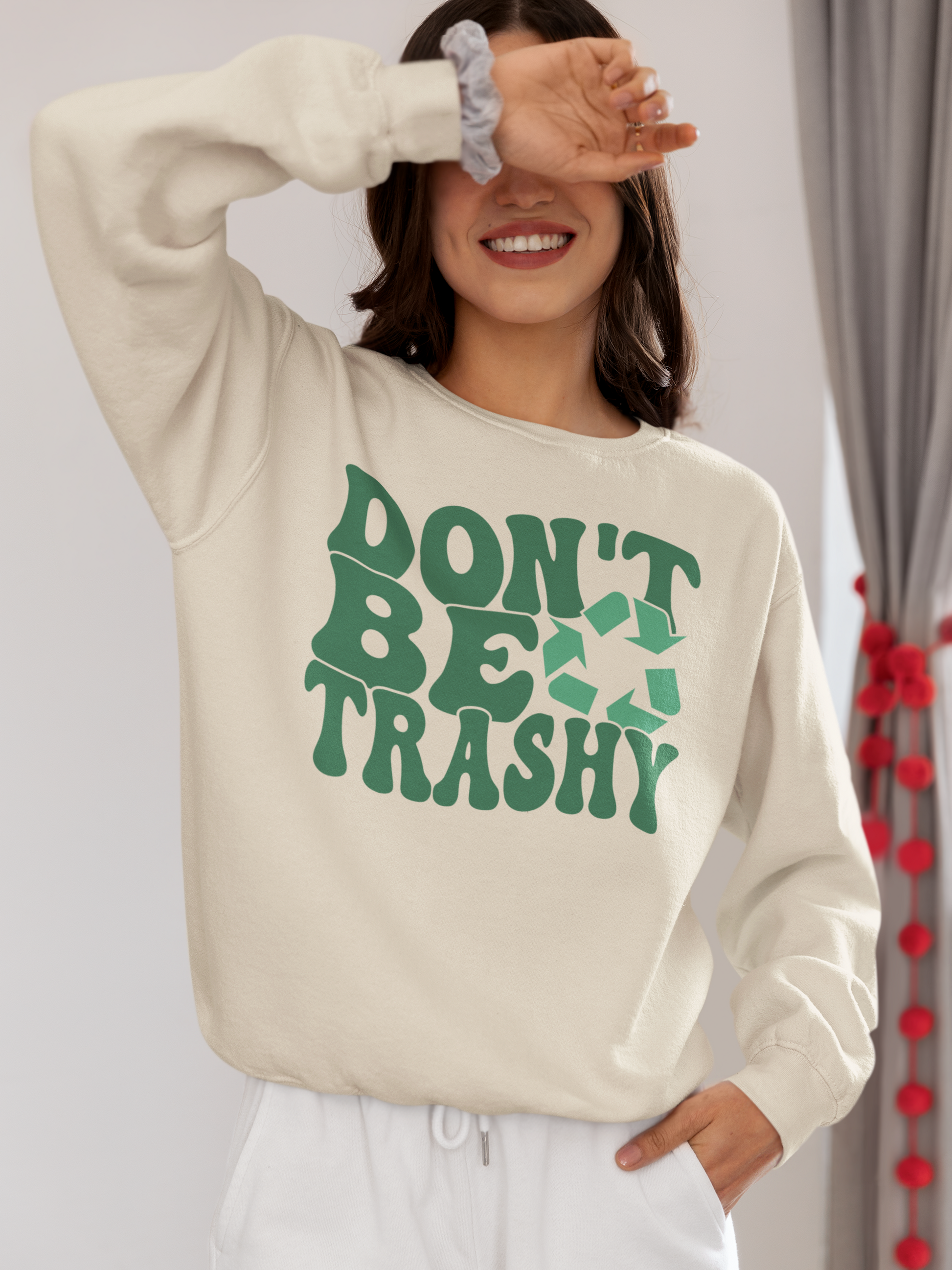 A girl covering her eyes wearing a beige "Don't Be Trashy" Sweatshirt