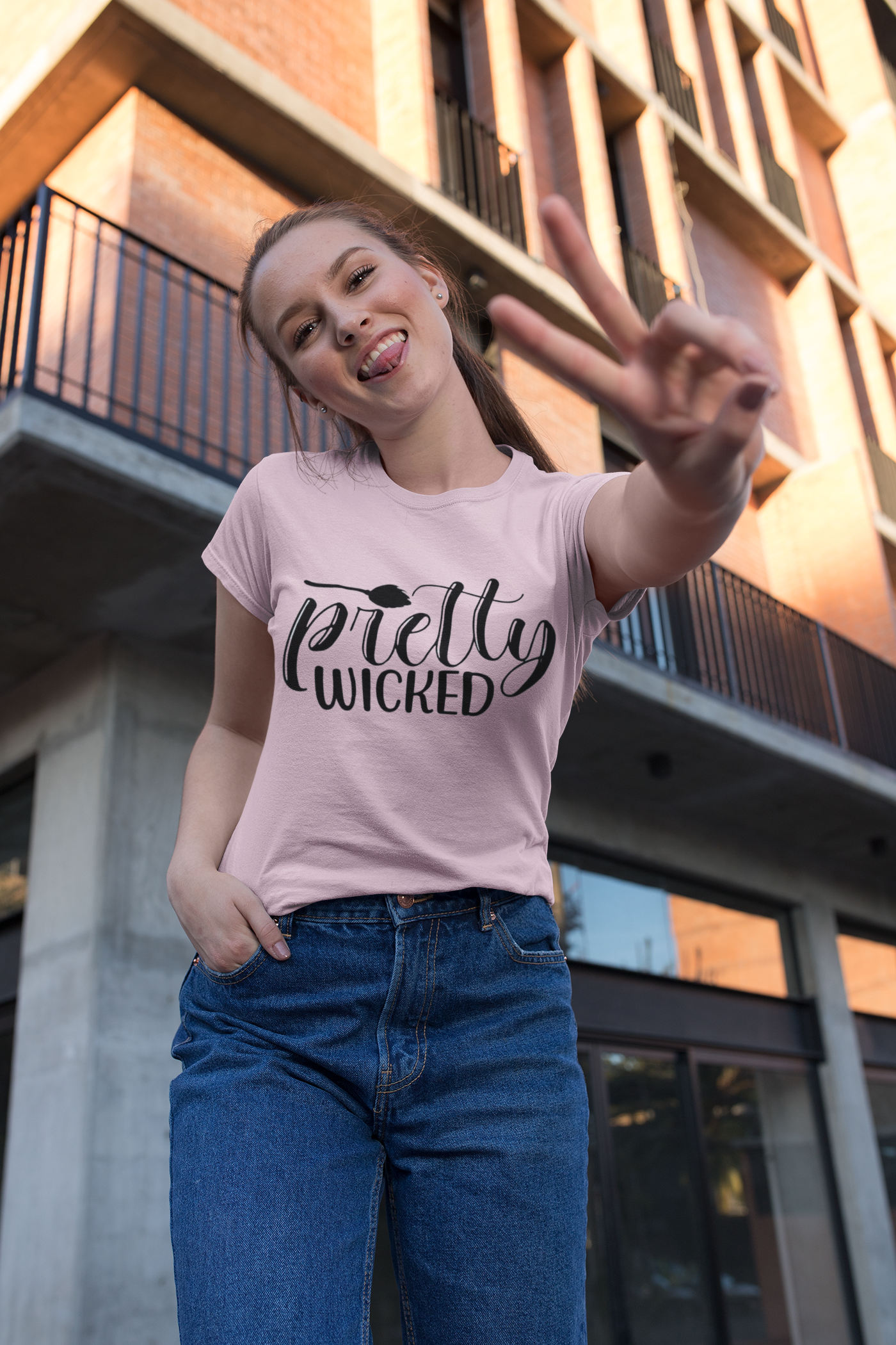 A girl smiling wearing "Pretty Wicked" T-Shirt holding up the peace sign.