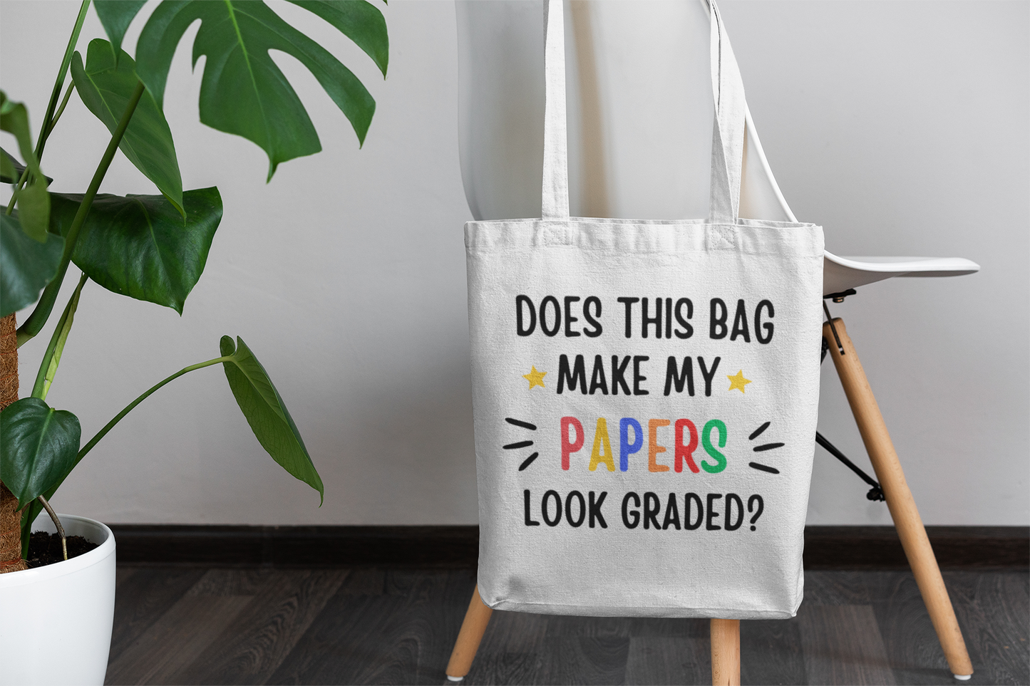 A "Does this make my papers look graded?" tote bag hanging on a chair.